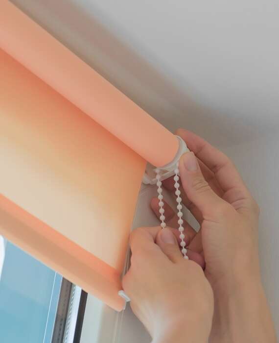 Installation of roller blinds. Close-up of female hands installing roller blinds on the window